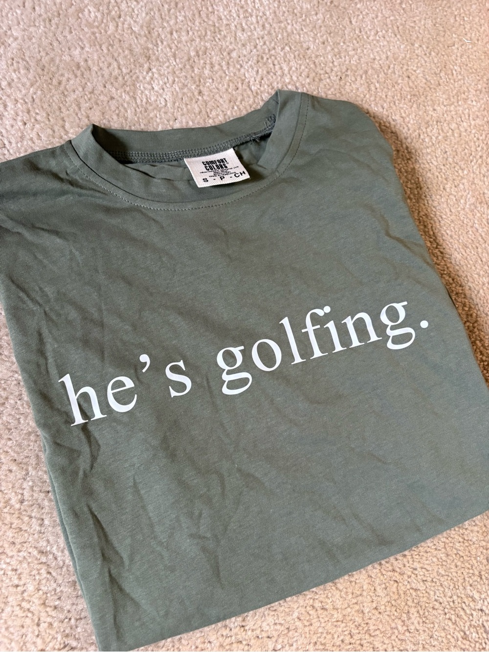 Comfort Colors Olive Green Kids Tee with White "he’s golfing." Graphic